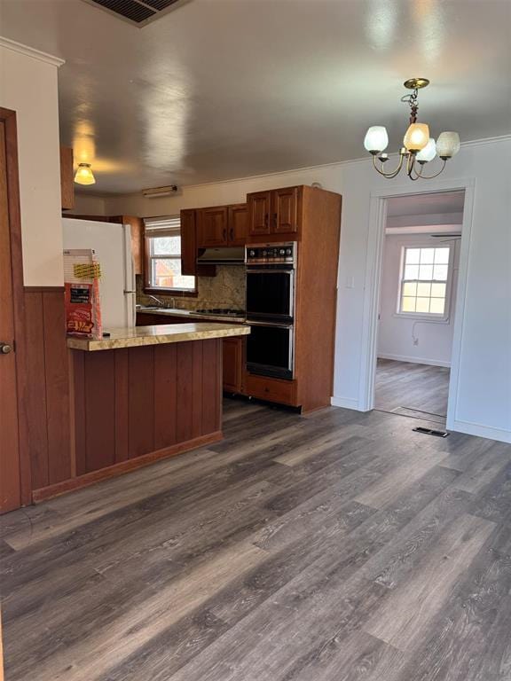 kitchen featuring multiple ovens, pendant lighting, dark hardwood / wood-style flooring, white fridge, and kitchen peninsula