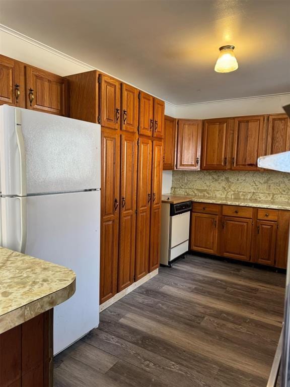 kitchen featuring tasteful backsplash, crown molding, dark wood-type flooring, and white appliances