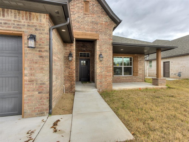 view of exterior entry featuring a yard and a patio