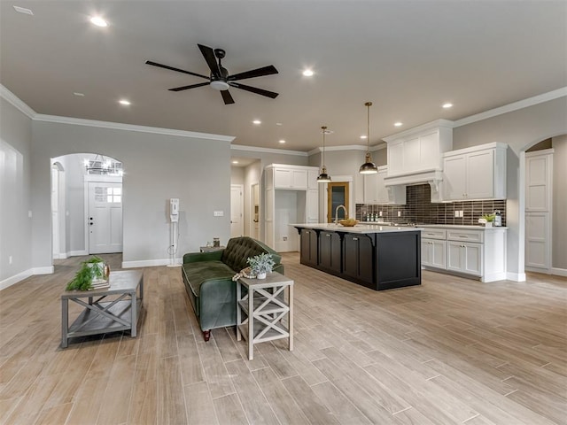 living room with ornamental molding, ceiling fan, light hardwood / wood-style flooring, and sink