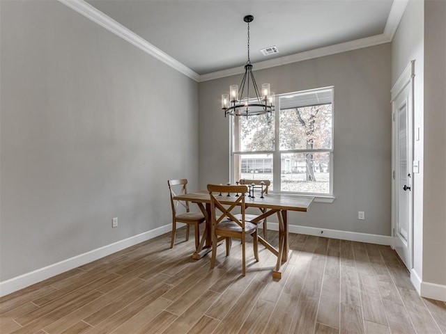 dining space featuring light hardwood / wood-style flooring, crown molding, and a notable chandelier