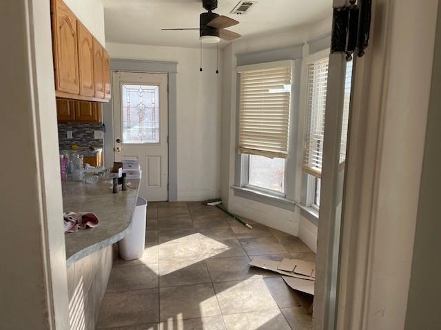 kitchen featuring ceiling fan, decorative backsplash, tile patterned floors, and a wealth of natural light