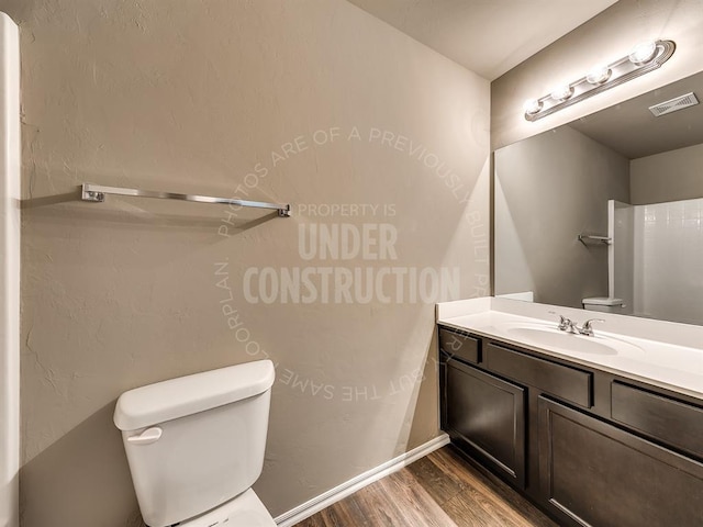 bathroom featuring vanity, hardwood / wood-style flooring, and toilet