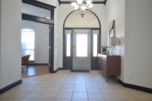 foyer entrance featuring a notable chandelier, baseboards, and light tile patterned floors