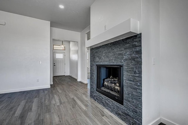 unfurnished living room featuring hardwood / wood-style floors and a stone fireplace