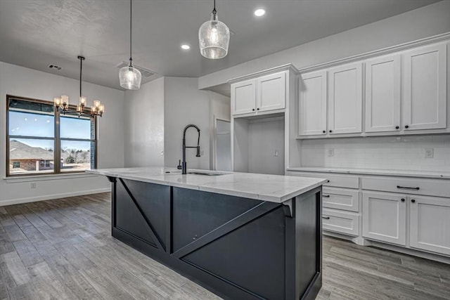 kitchen with light stone countertops, decorative light fixtures, white cabinetry, decorative backsplash, and sink