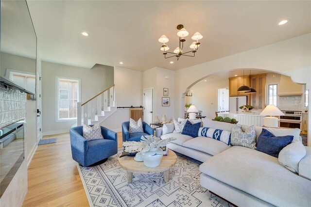 living room featuring a wealth of natural light, light hardwood / wood-style flooring, and an inviting chandelier