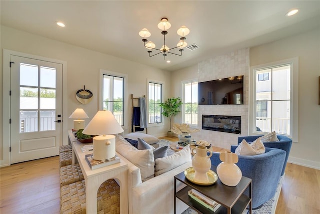 living room with a fireplace, light hardwood / wood-style flooring, and a notable chandelier