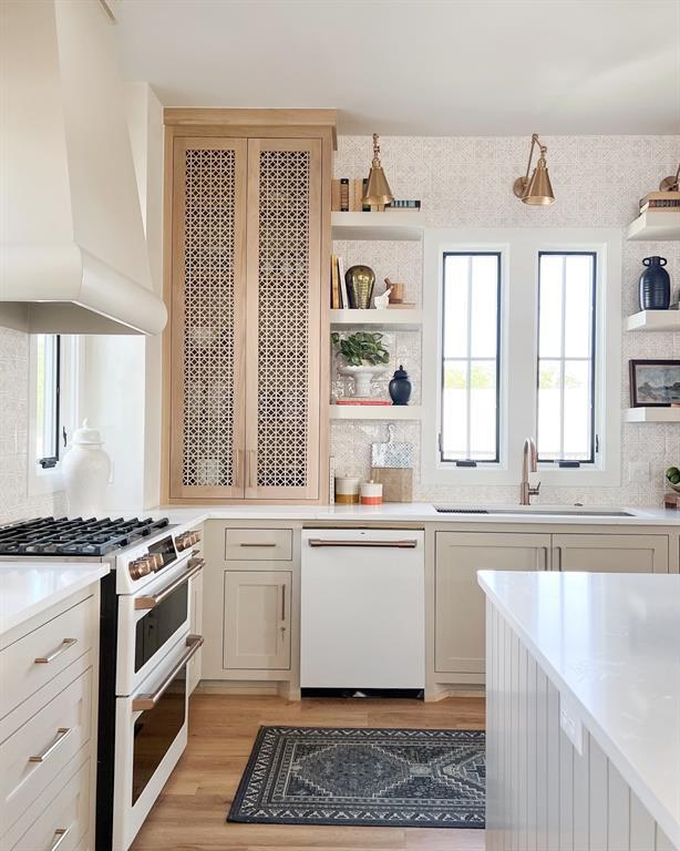 kitchen featuring sink, premium range hood, light wood-type flooring, backsplash, and white appliances