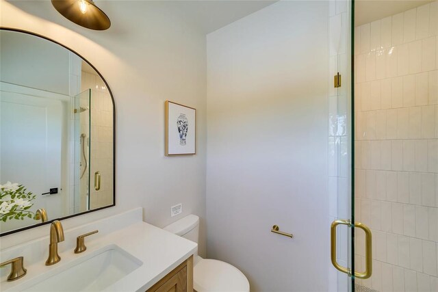 bathroom with a shower with door, toilet, and vanity