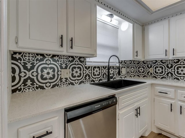 kitchen with tasteful backsplash, stainless steel dishwasher, sink, and white cabinets