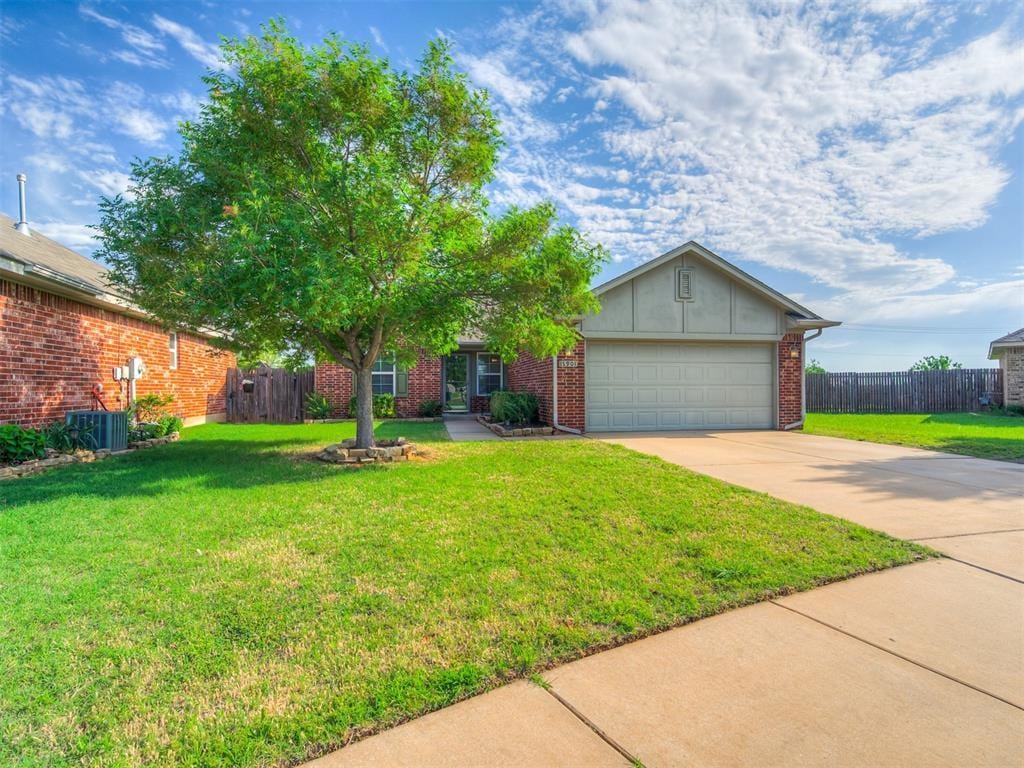 ranch-style home featuring central AC, a garage, and a front lawn