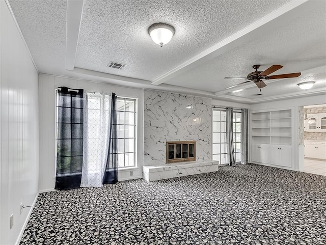 unfurnished living room with ceiling fan, a high end fireplace, built in features, and a textured ceiling