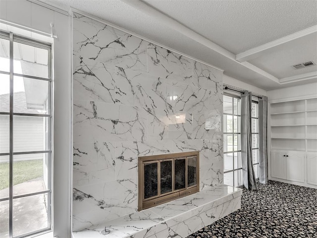 unfurnished living room with crown molding, built in features, a premium fireplace, and a textured ceiling