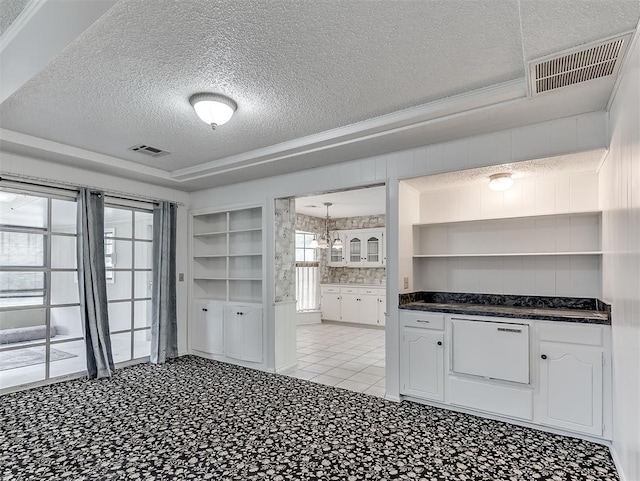 kitchen with a tray ceiling, a textured ceiling, and white cabinets