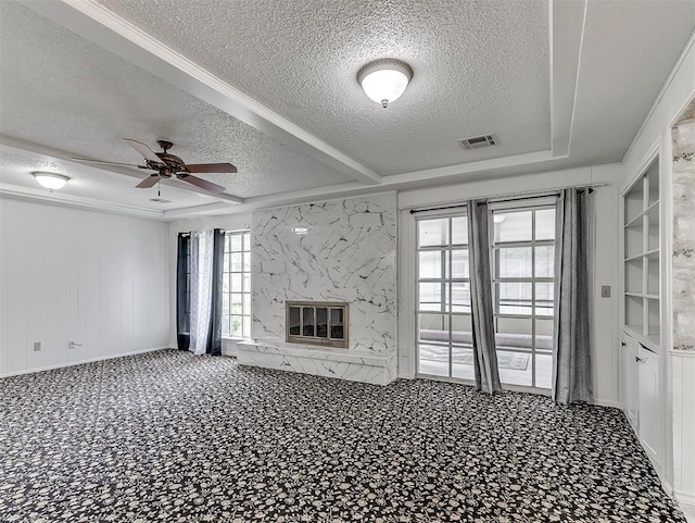 unfurnished living room with a premium fireplace, ceiling fan, built in features, and a textured ceiling