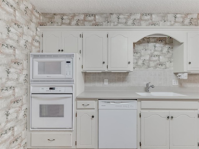 kitchen with sink, white appliances, white cabinetry, backsplash, and a textured ceiling