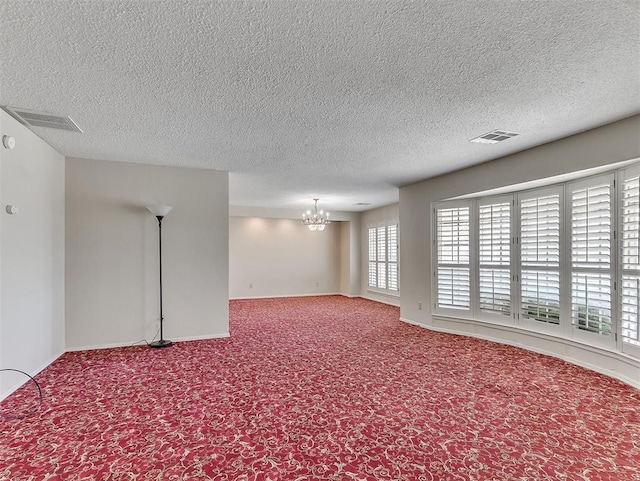 carpeted spare room featuring a chandelier and a textured ceiling