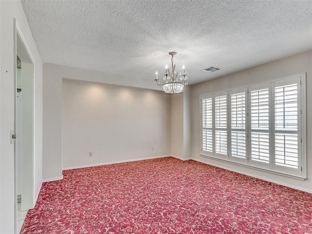 spare room featuring a notable chandelier and a textured ceiling