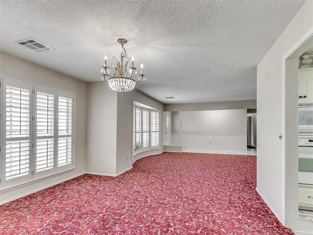 carpeted empty room with an inviting chandelier and a textured ceiling