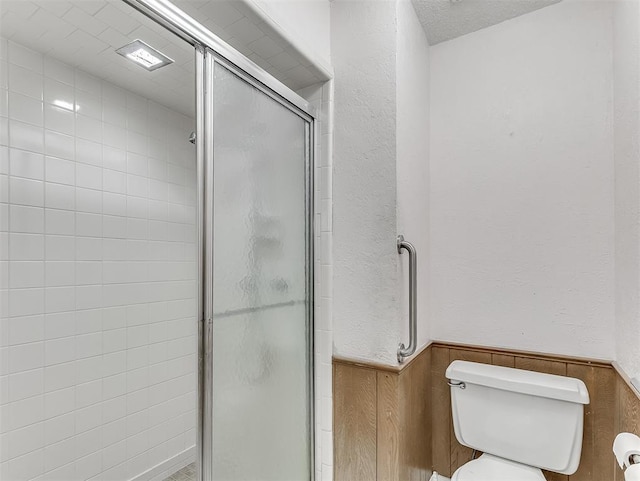 bathroom featuring a shower with shower door and toilet