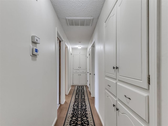 hallway featuring hardwood / wood-style flooring and a textured ceiling