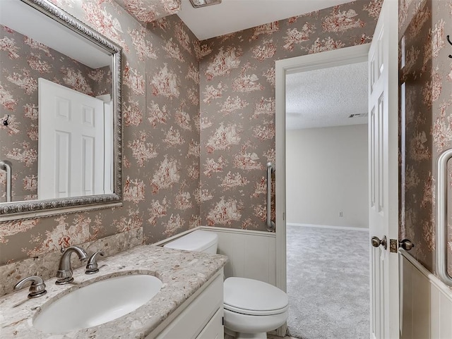 bathroom with vanity, a textured ceiling, and toilet