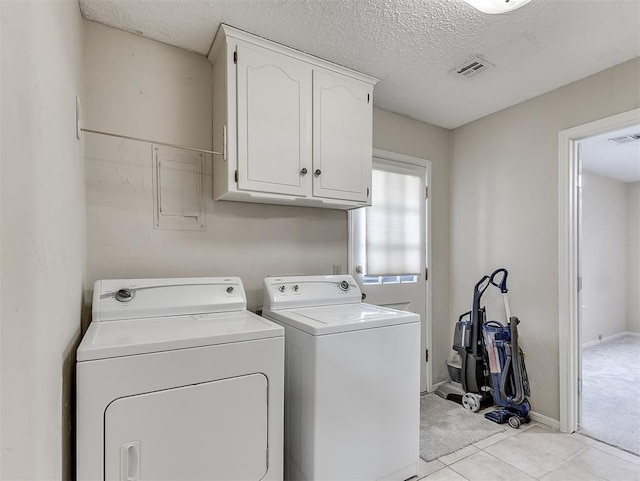 clothes washing area with cabinets, separate washer and dryer, a textured ceiling, and light tile patterned floors