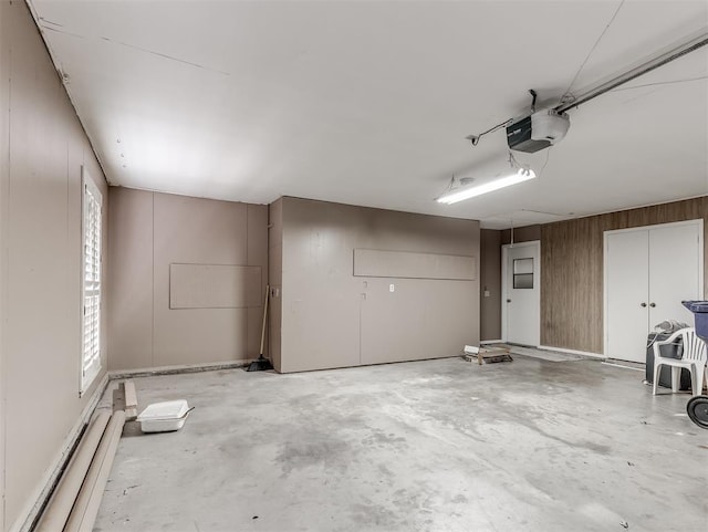 garage with a garage door opener, wooden walls, and baseboard heating