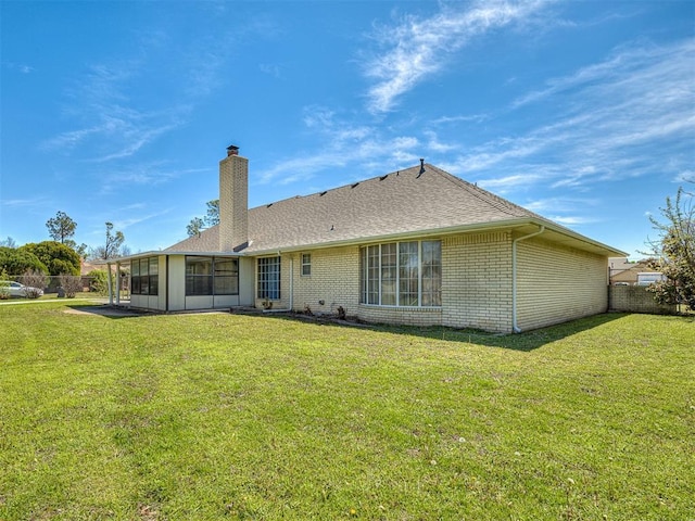 rear view of property featuring a sunroom and a lawn