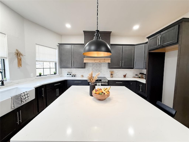 kitchen with sink, hanging light fixtures, decorative backsplash, and stainless steel electric stove