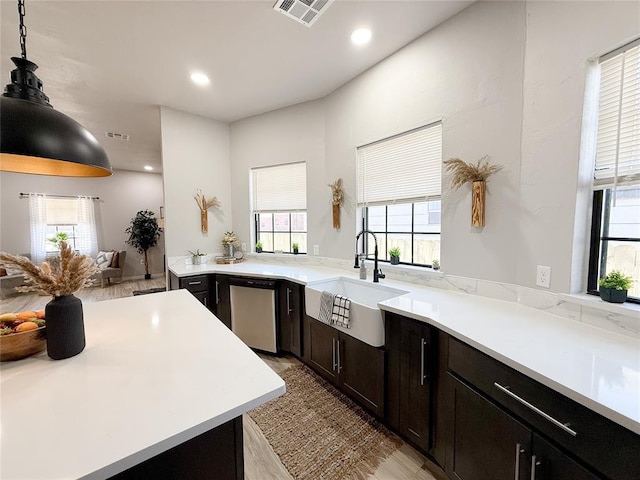 kitchen with dishwasher, decorative light fixtures, sink, kitchen peninsula, and light wood-type flooring