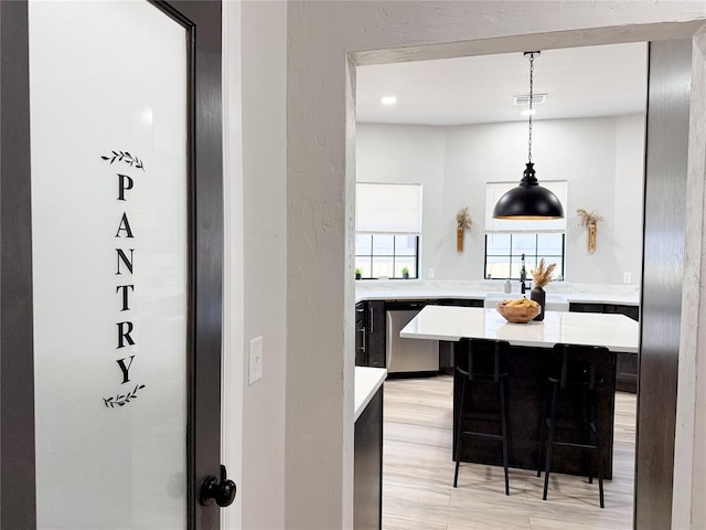 kitchen featuring dishwasher, hanging light fixtures, kitchen peninsula, a breakfast bar, and light hardwood / wood-style flooring