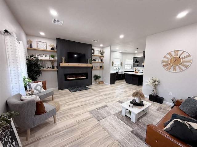 living room featuring a large fireplace and light wood-type flooring