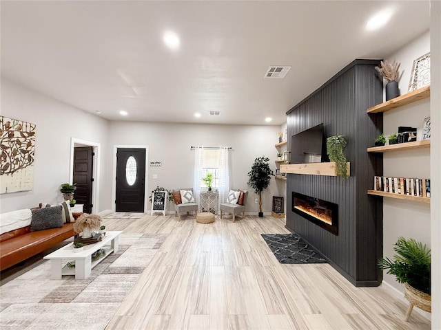 living room with a large fireplace and light hardwood / wood-style flooring