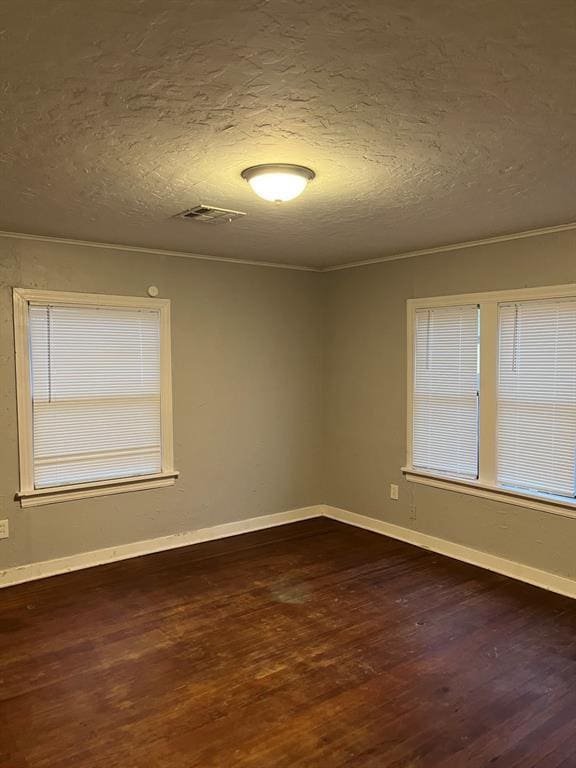 spare room featuring crown molding, dark hardwood / wood-style floors, and a textured ceiling