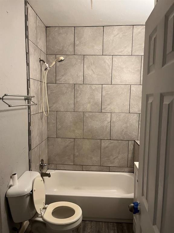 full bathroom with tiled shower / bath, hardwood / wood-style floors, vanity, and toilet