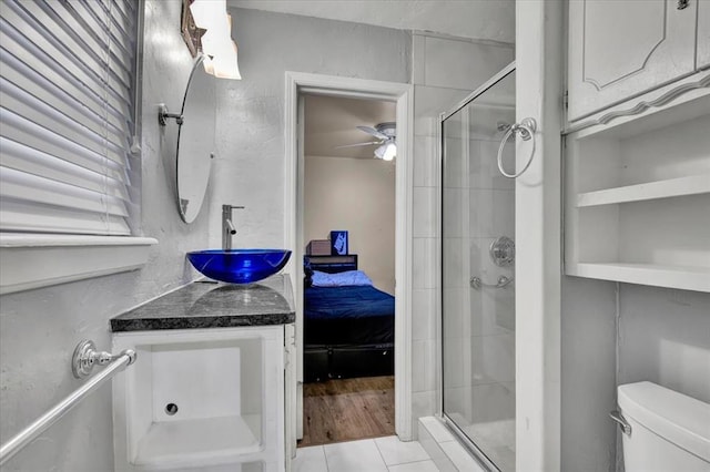 bathroom featuring vanity, a shower with shower door, tile patterned floors, and toilet