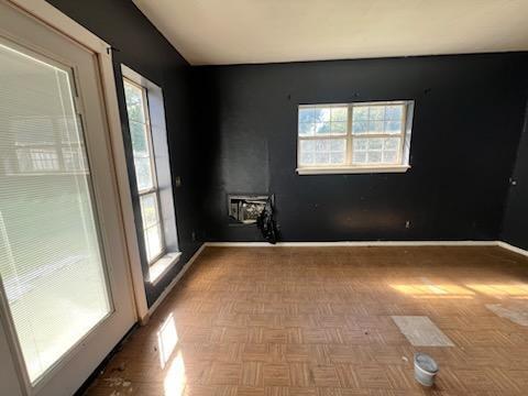 unfurnished room featuring parquet flooring and plenty of natural light