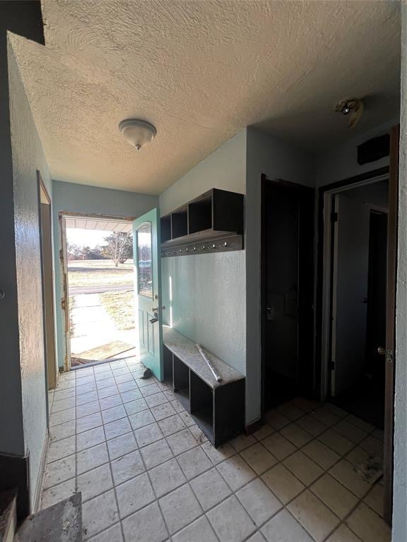 mudroom with light tile patterned floors and a textured ceiling