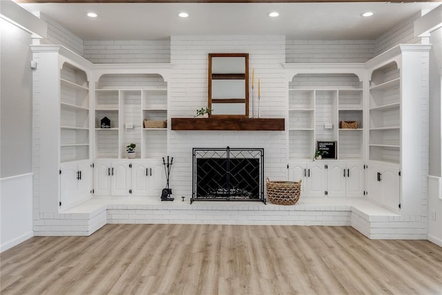 unfurnished living room with a brick fireplace and light hardwood / wood-style floors