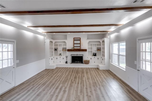 unfurnished living room featuring light hardwood / wood-style floors, beam ceiling, and a fireplace