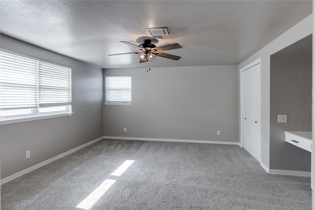 carpeted spare room featuring ceiling fan and a textured ceiling