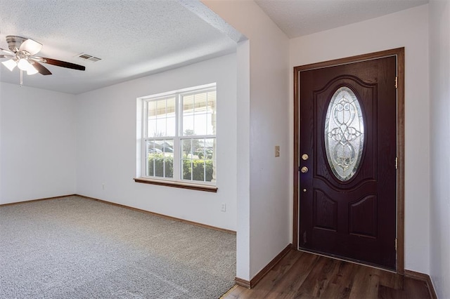 foyer featuring visible vents, baseboards, a textured ceiling, and ceiling fan