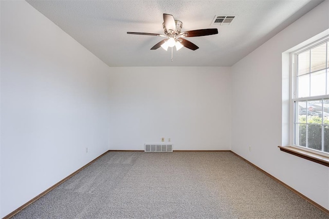 carpeted spare room with baseboards, visible vents, a textured ceiling, and ceiling fan