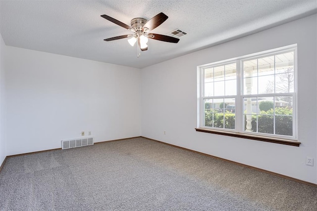 unfurnished room featuring a textured ceiling, visible vents, carpet floors, and ceiling fan