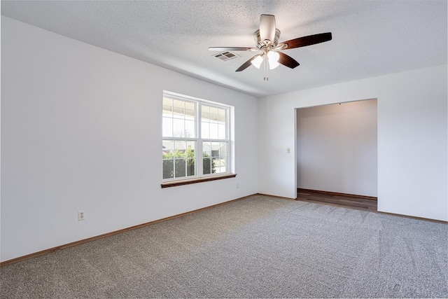 carpeted spare room featuring baseboards, visible vents, a textured ceiling, and ceiling fan