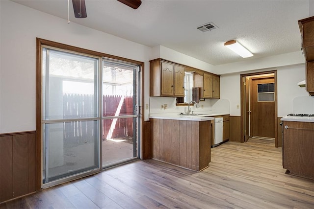 kitchen featuring light wood-style flooring, wainscoting, light countertops, and a sink