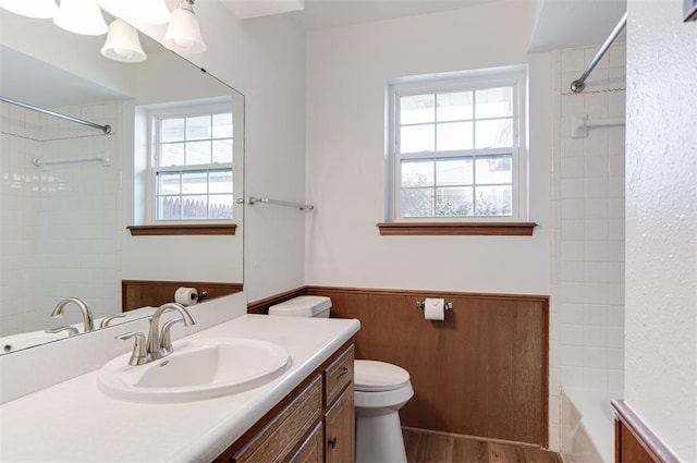 bathroom featuring wooden walls, toilet, wainscoting, wood finished floors, and vanity