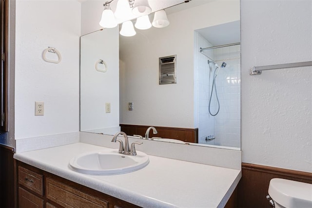 full bath with toilet, walk in shower, wainscoting, and vanity